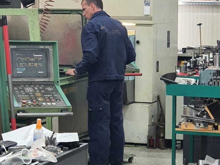 Operater za upravljačkim pultom CNC glodalice MAHO; iza njega mašina za eroziju žicom AGIE (2020).