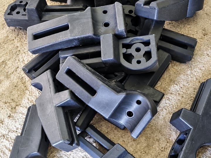 Gomila crnih brizganih plastičnih nosača sa otvorima i žlebovima.