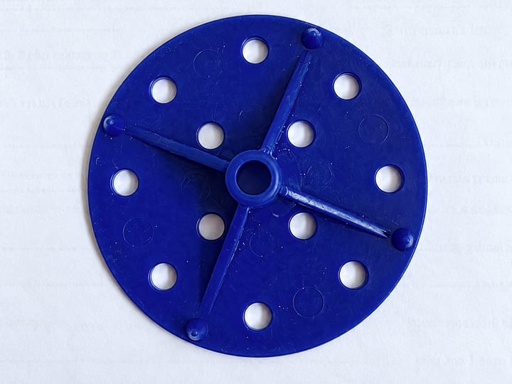 Plavi brizgani plastični disk sa otvorima i četiri rebra, na beloj podlozi.
