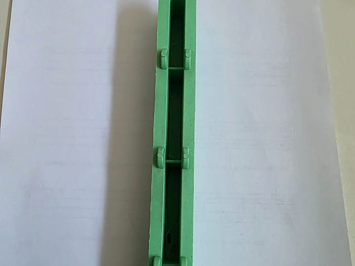 Dugačak zeleni brizgani plastični profil sa poprečnim rebrima, na papiru.
