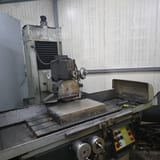 Ravna brusilica sa magnetnim stolom i brusnom pločom pod štitnikom, u radionici.