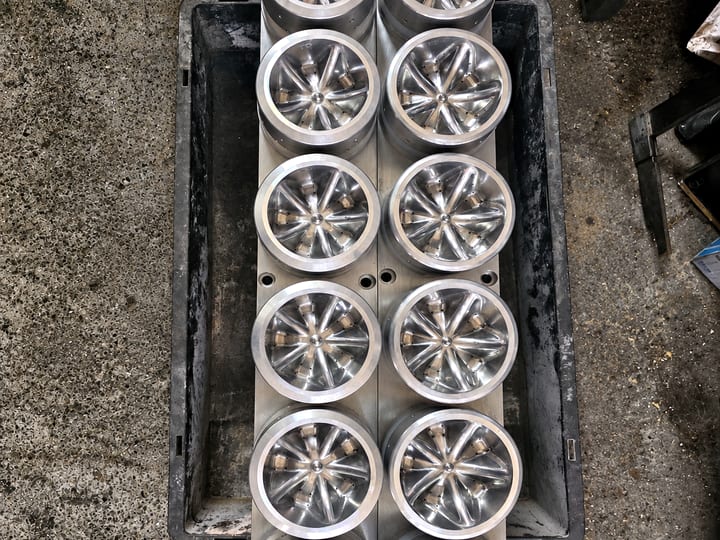 Dvanaest aluminijumskih umetaka za dno boce sa zvezdastim profilom, složenih u plastičnu kutiju.