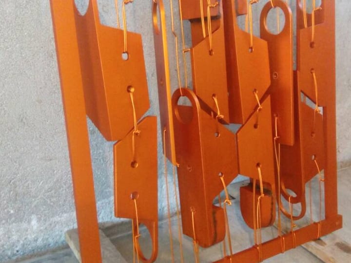 Narandžasti praškasto obojeni limeni delovi okačeni na ram.