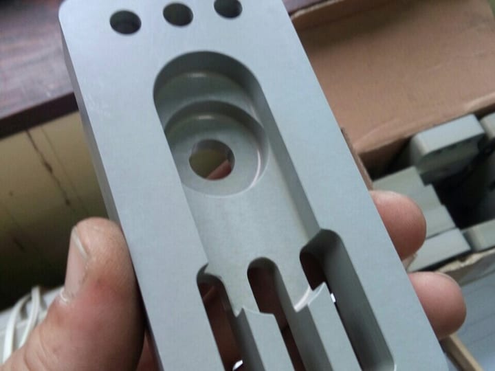Ruka drži glodanu aluminijumsku ploču sa prorezima i otvorima.