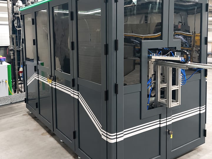 Automatska PET duvaljka ABM 5C-5002 u tamnosivom kućištu sa staklenim vratima i zelenom LED trakom, u proizvodnoj hali.